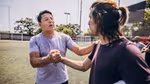 Two people on a sports field grasping their right hands.