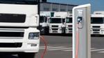 An electric truck recharges, with a fleet of electric trucks in the background.