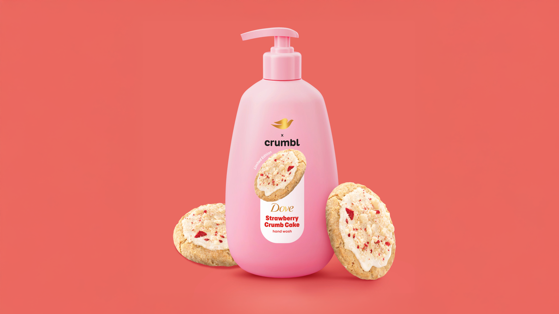 A pink bottle of Strawberry Crumb Cake hand wash from the Dove Crumbl collaboration. Crumbl cookies either side. Coral pink background.