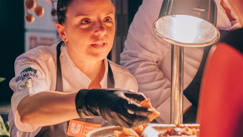 A Unilever Food Solutions chef smiling as she plates up.