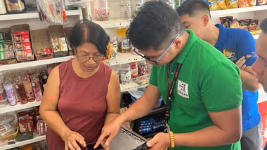 A man helps a woman work with an app in a store.