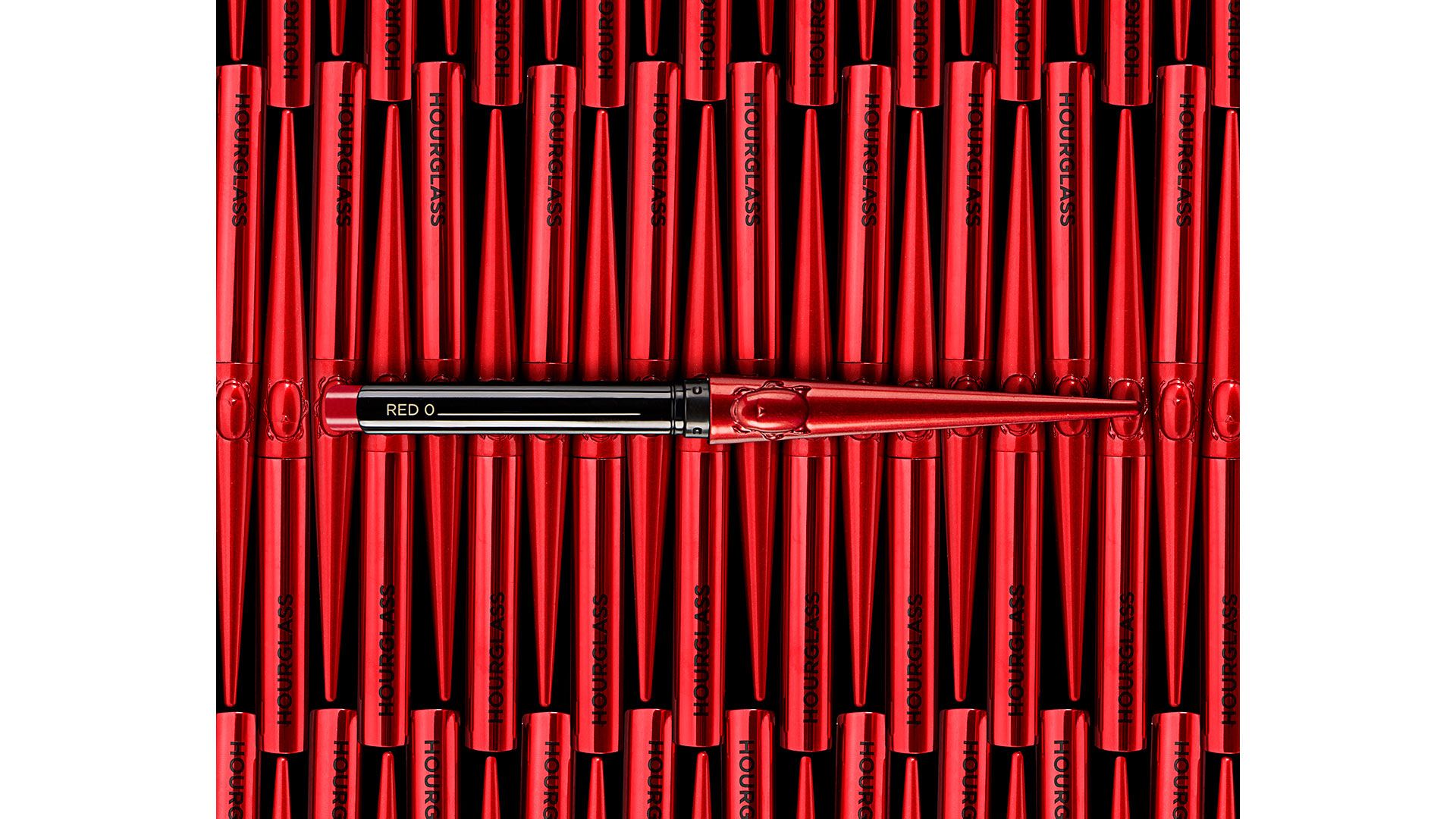 A photo of Hourglass 100% vegan and carmine-free Red Zero lipstick. One open product sits above an array of metallic red cases.