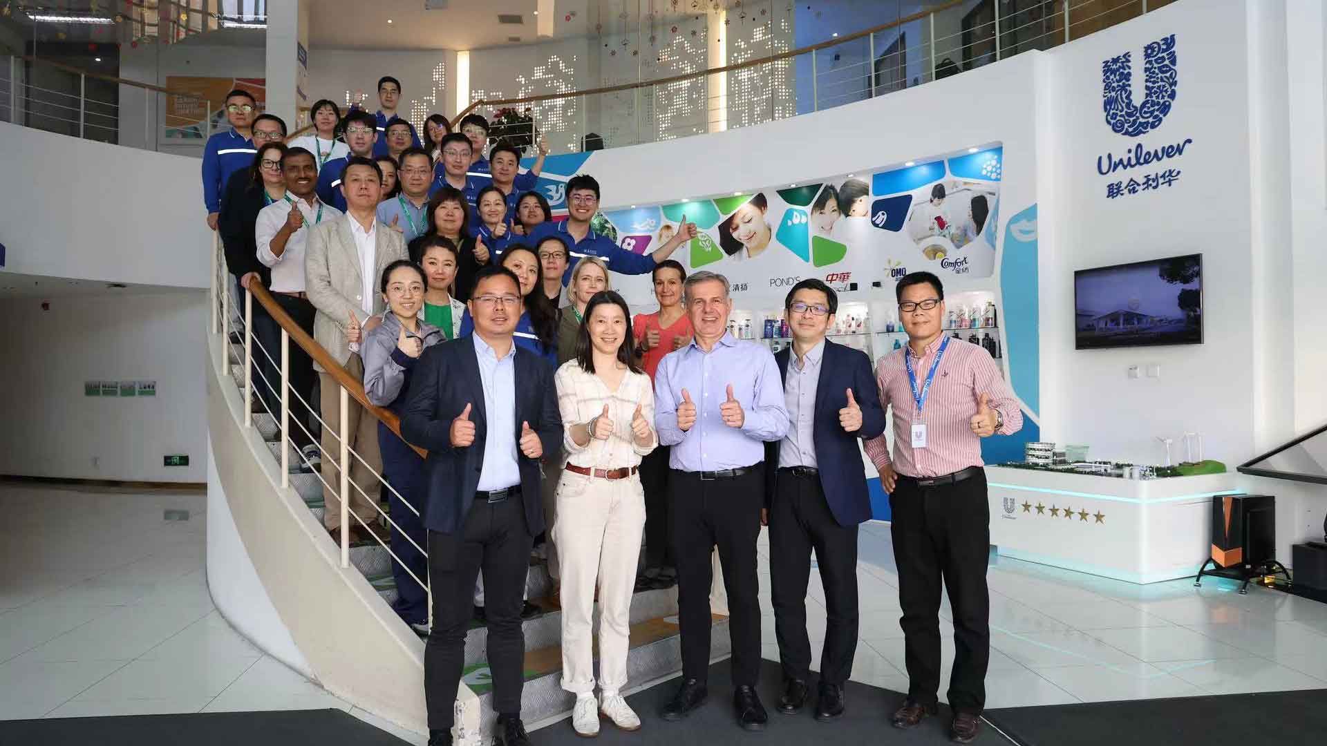 Reginaldo Ecclissato smiling with a team of colleagues on a staircase