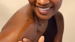 Close-up of a person applying a skincare product to their shoulder, showing smooth skin and a gentle smile.