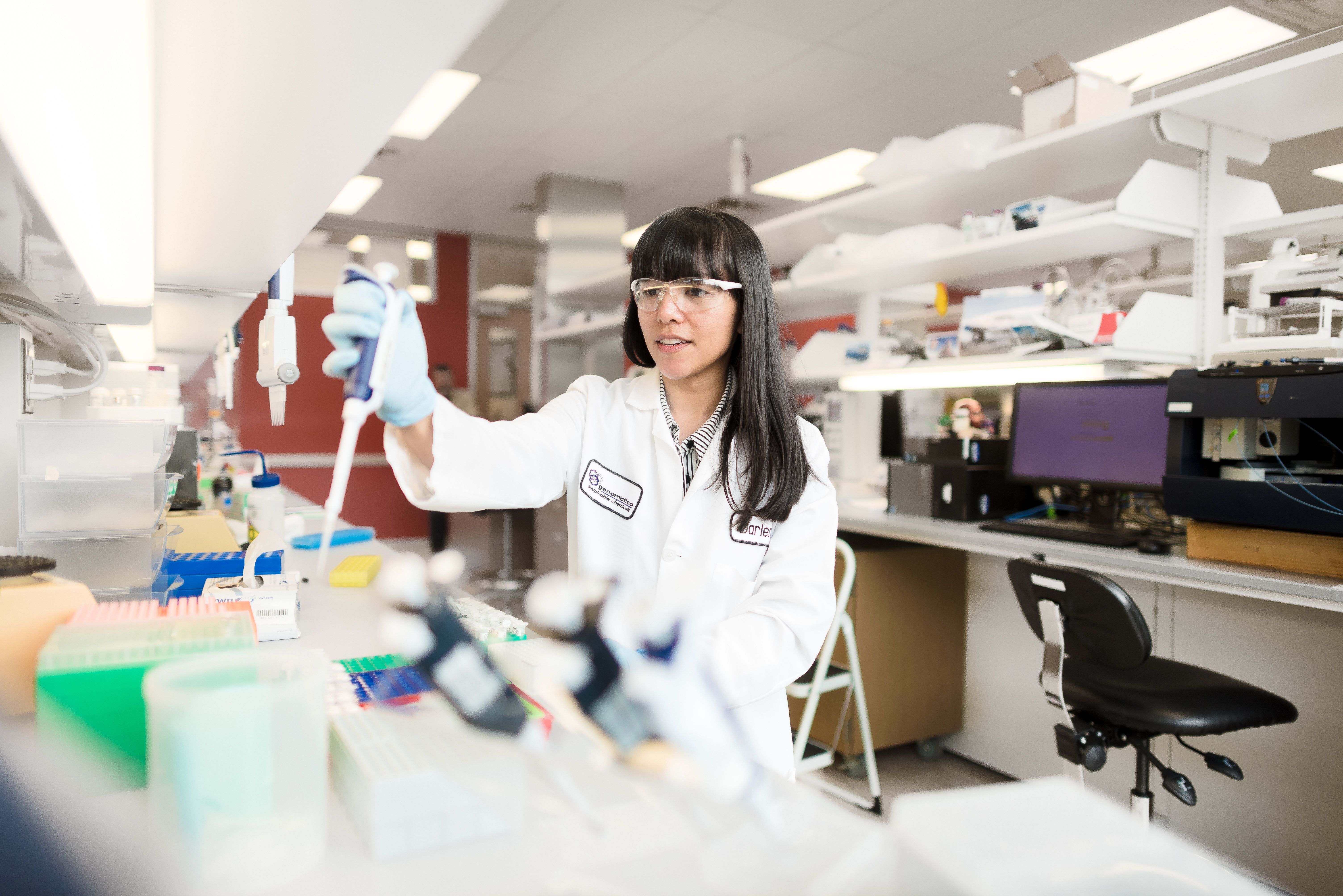 A woman in a white lab coat working at one of Geno’s biotech labs