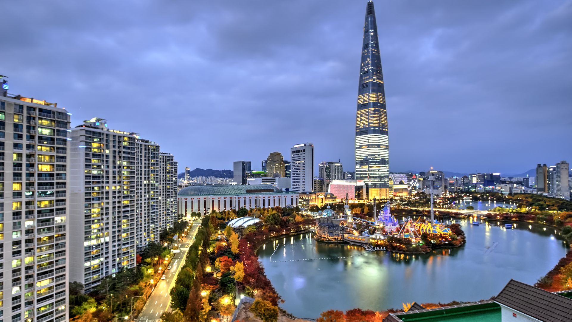 The skyline of Seoul, South Korea lit up against a deep blue sky.